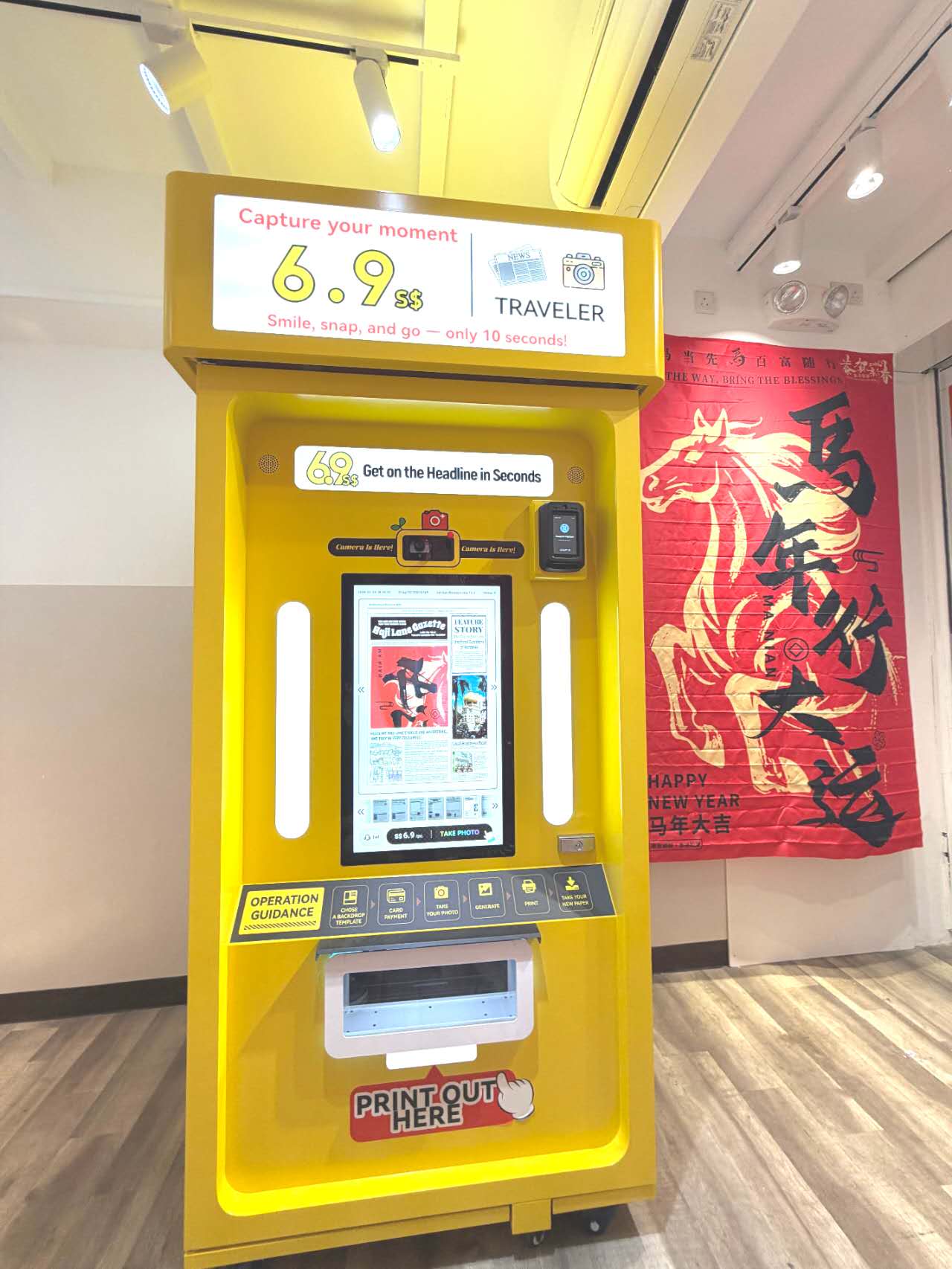 Yellow newspaper photo booth with screen, camera and print opening